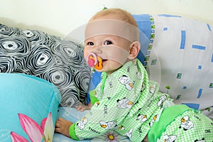 One year old baby vigorously crawls to his goal. Little cheerful boy in a light green suit with sheep.