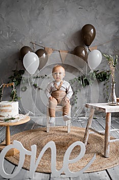 One year old birthday, rustic minimalist decorations and a little boy, balloons and a wooden background, birthday cake