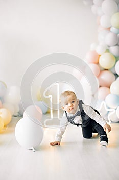 One year old boy is celebrating his first birthday among a lot of balloons