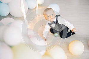 One year old boy is celebrating his first birthday among a lot of balloons