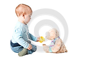 One year old boy feeding his teddy bear