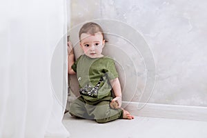 One year old boy is kneeling near white sunblind