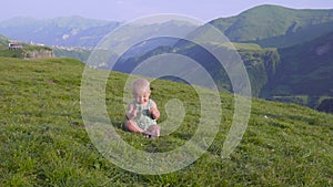 One year old boy learn to walk on the background of mountains