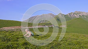 One year old boy learn to walk on the background of mountains