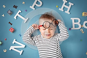 One year old child lying with spectacles and letters