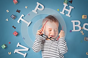 One year old child lying with spectacles and letters