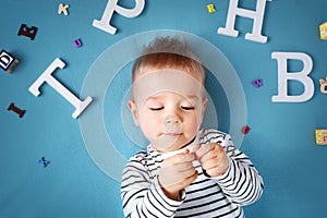 One year old child lying with spectacles and letters