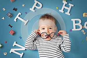 One year old child lying with spectacles and letters