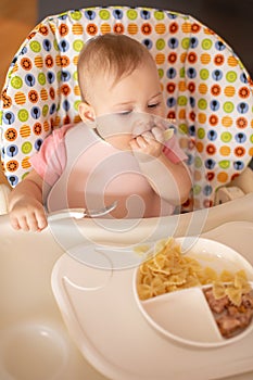 One year old girl having balanced meal in baby eating chair, healthy balanced nutrition for child