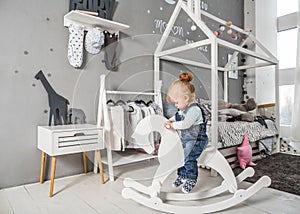 One-year-old girl playing near in the room with a toy horse, ska