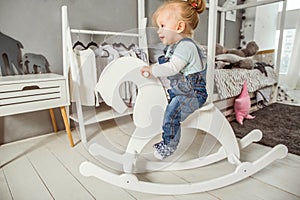 One-year-old girl playing near in the room with a toy horse, ska