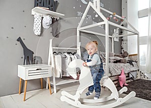 One year old girl playing near in the room with a toy horse, ska