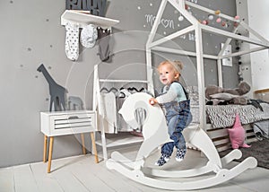 One year old girl playing near in the room with a toy horse, ska