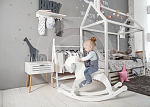 One year old girl playing near in the room with a toy horse, ska