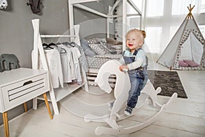 One year old girl playing near in the room with a toy horse, ska