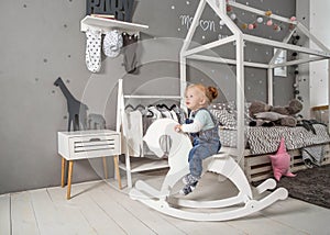 One year old girl playing near in the room with a toy horse, ska