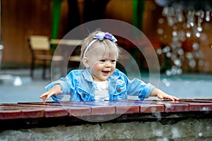 One year old girl smiling near the fountain