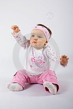 One year old infant trying to catch soap bubbles.