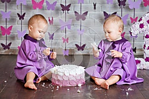 One year old twin girls selebrating they 1st birthday and eating smash-cake