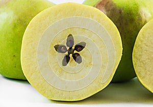One yellow apple cut in half on a white background with apples