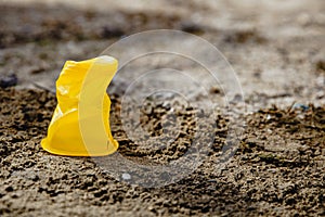 One yellow crumpled plastic Cup standing on the ground. Concept of environmental disaster