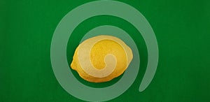 One yellow fresh lemon on green background