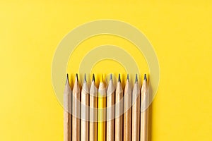 One yellow pencil standing out from the series of gray pencils.