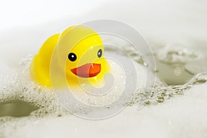One yellow rubber duck with soap bubble bath, light background with bubbles. Kids spa concept. Children`s bath time concept