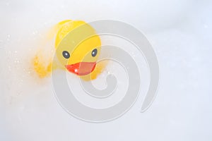 One yellow rubber duck with soap bubble bath, light background with bubbles. Kids spa concept. Children`s bath time concept