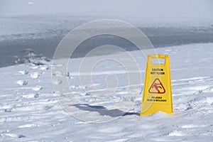 One yellow sign board caution wet floor over a frozen lake Horizontal