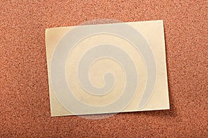 One yellow sticky post note closeup cork board background