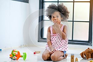 One young African girl sit and express of frighten or shock during plays some toys in the living room