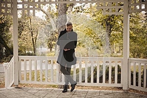 One young businessman, 20-29 years old, entrepreneur, holding laptop in hand, casually working in public park outdoors.