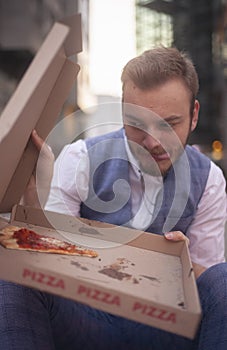 One young businessman resisting to eat his pizza