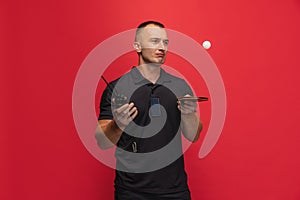 One young caucasian man with ping pong racket and walkie-talkie playing table tennis over red background.