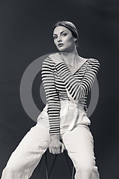 one young Caucasian woman 20s, 20-29 years, fashion model sitting bar stool, posing, studio, white background, horizontal stripe