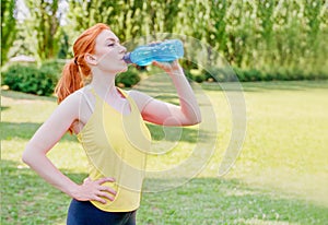 One young fitness woman wearing sport clothes training outdoors drinking water