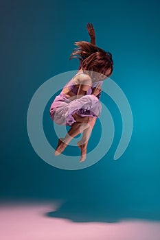 One young flexible contemp dancer in lilac dress dancing isolated on gradient blue white background in neon.