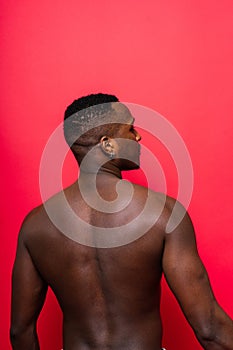 One young handsome african man topless portrait in studio on red background