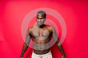 One young handsome african man topless portrait in studio on red background