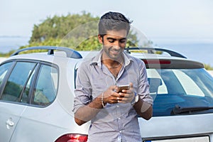 One young handsome Indian man smiling holding looking at mobile phone