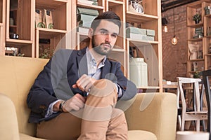 One young handsome man sitting sofa coffee bar indoors interior