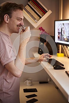 One young  man, 20-25 years old, using computer, with standing desk. Smiling and happy