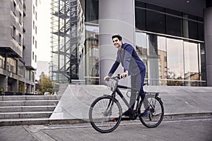 One young man, 20-29 years old, wearing suit, looking smiling. riding, pedaling standing, fancy bicycle. full length body. modern