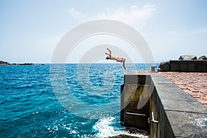 One young man jumping off a cliff doing a backflip to the water - alone fitness and healthy teenager having fun enjoying alone the