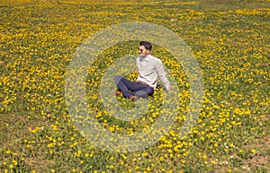 One young man, sitting flower field, outodoors, sunny day