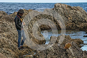 One young man stands on ocean rocks by the sea