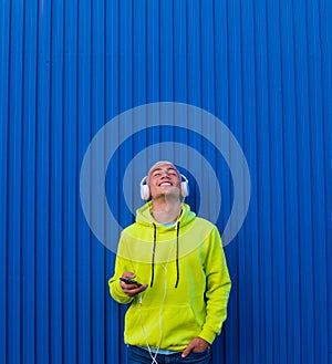 One young man or teenager millennial listening music with his phone and headphones looking up enjoying music and the moment -