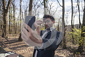 One young man, using smartphone to make a selfie, outdoors in nature