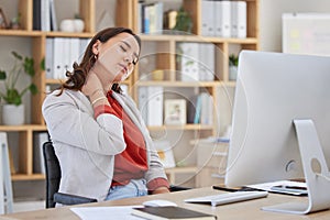 One young mixed race female businesswoman sitting at her desk in front of her computer experiencing neck pain and